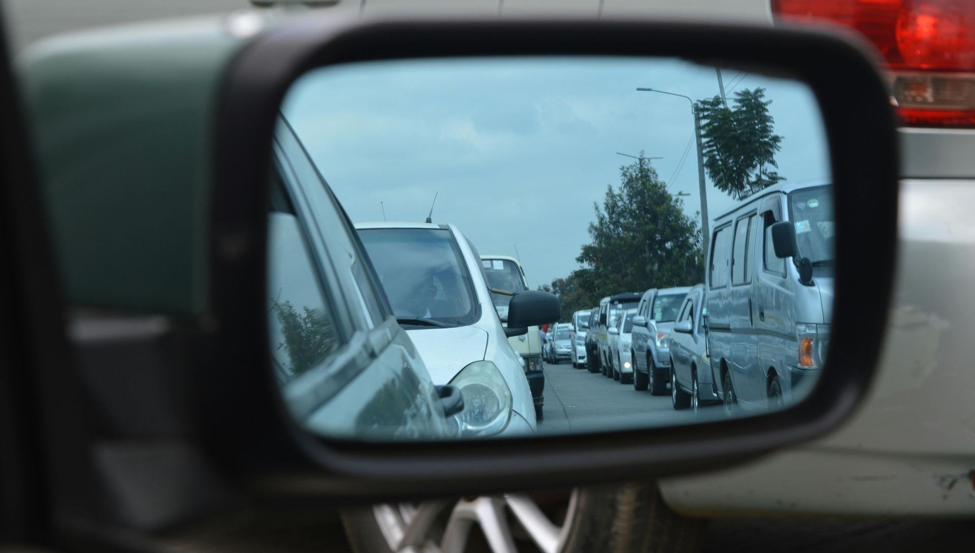 A rear view mirror shows a row of cars on a street