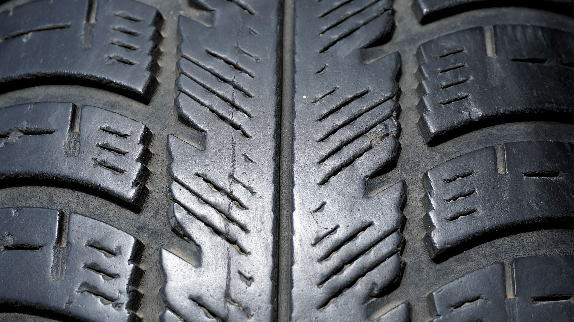 Close-up of a black tire tread pattern with grooves, showing wear.