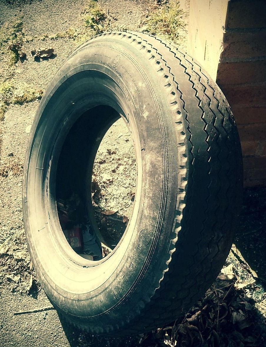 A tire is sitting on the ground in front of a brick building
