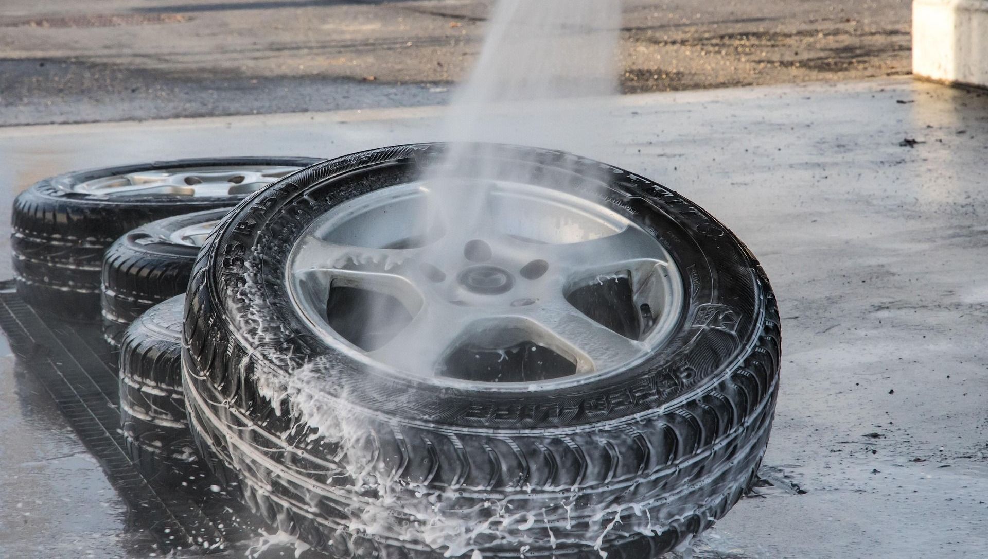 A person is washing a tire with a high pressure washer.