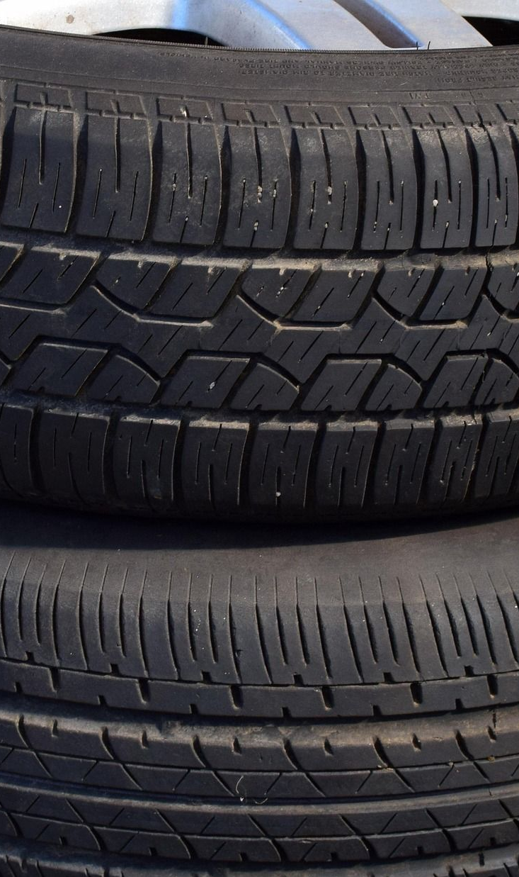 Two stacked black tires with textured treads, resting indoors.