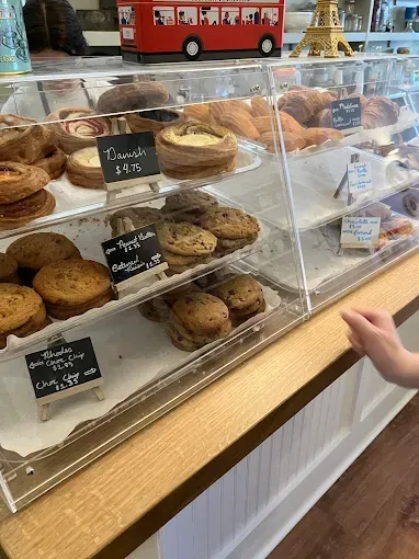 Bakery display case with pastries; hand reaching towards it.