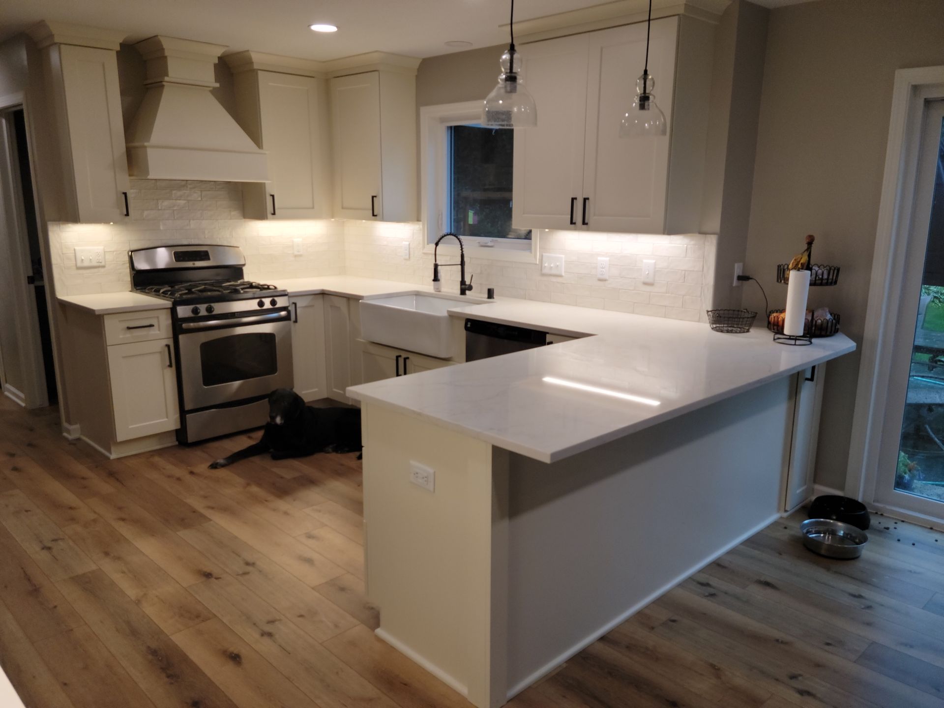 Modern kitchen with white cabinets, stainless steel stove, island, and wood floors.