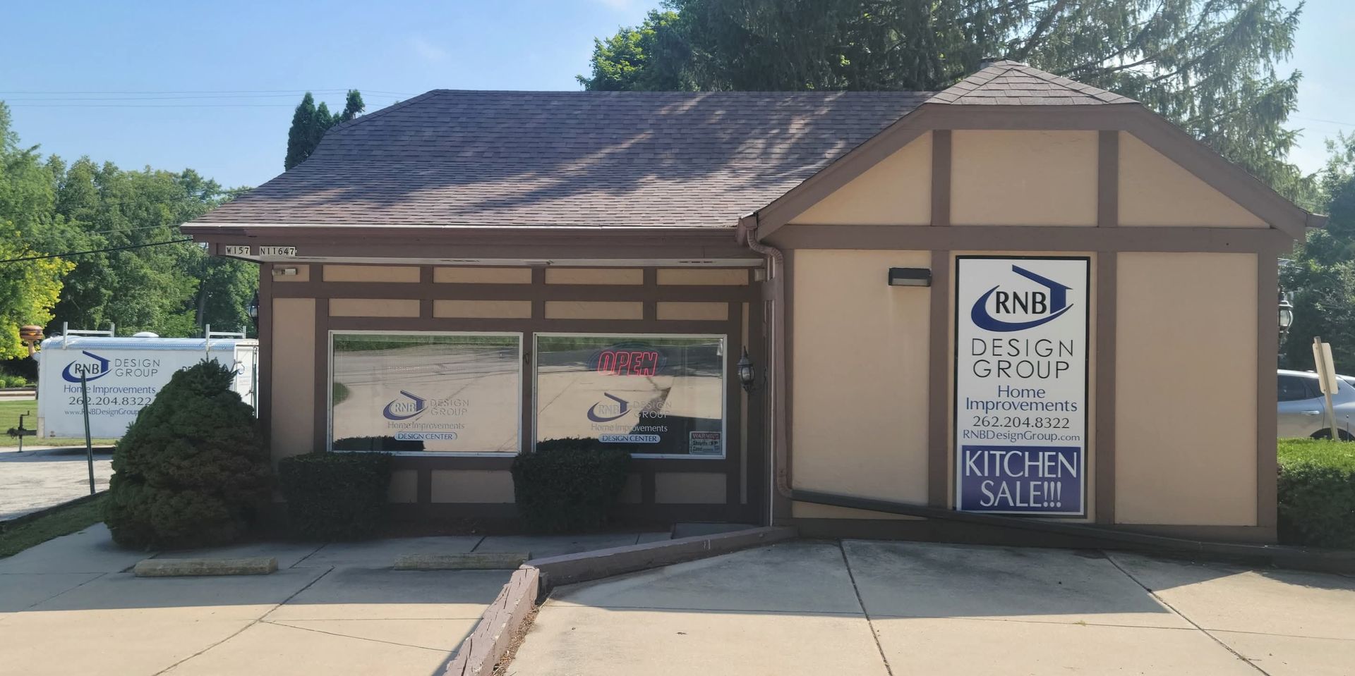 Small tan building with a sign and garage-style bay doors under a sunny sky