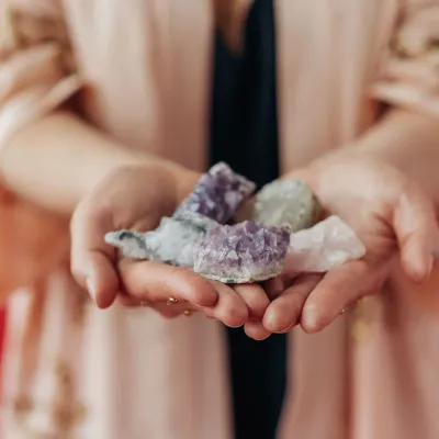 una donna tiene in mano un cristallo di pietre viola e bianche .