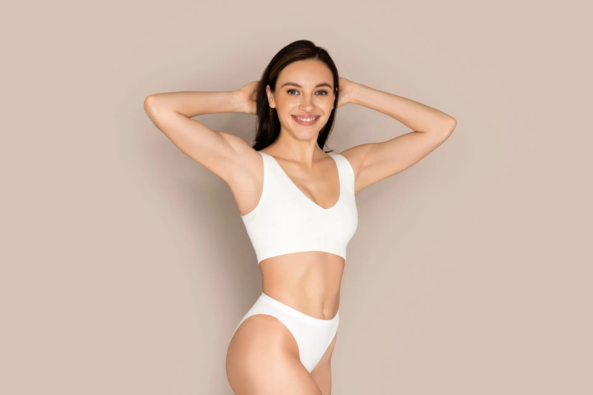 una donna in lingerie bianca è in piedi con le mani dietro la testa .