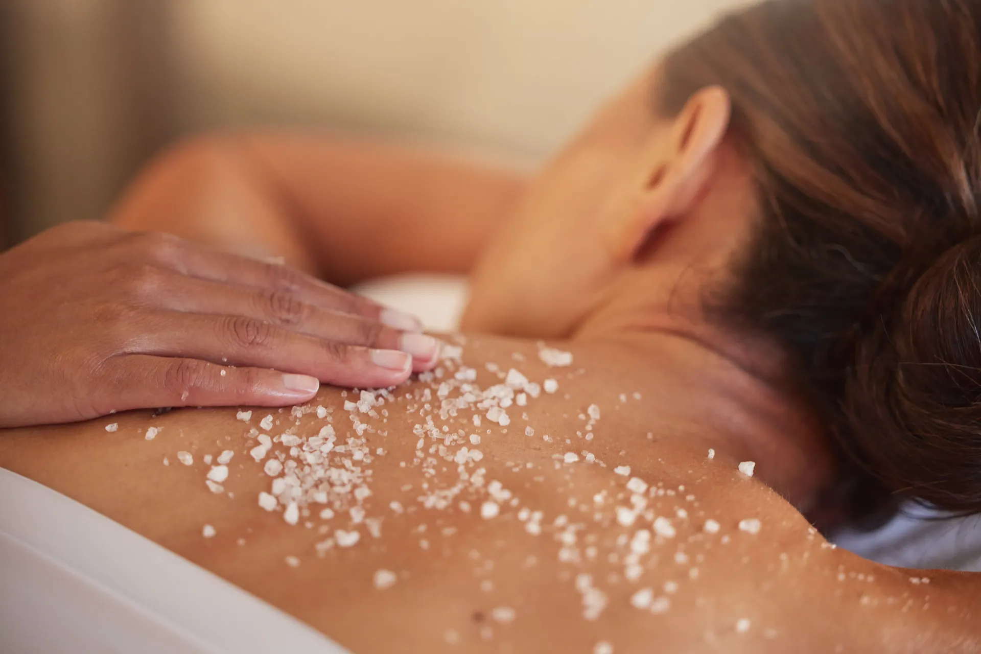 una donna sta ricevendo un massaggio con sale sulle spalle .
