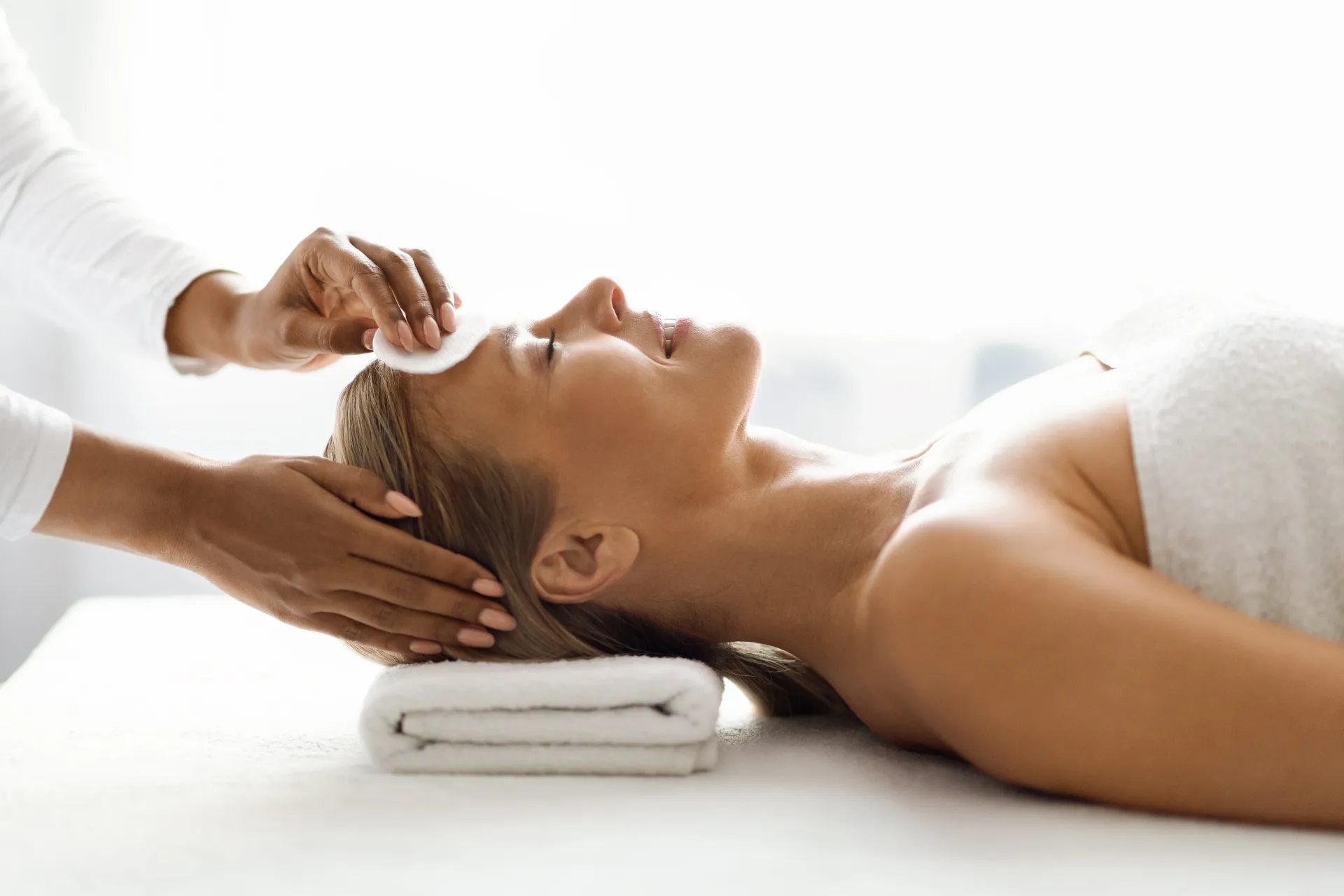 una donna è sdraiata su un tavolo e riceve un massaggio al viso .