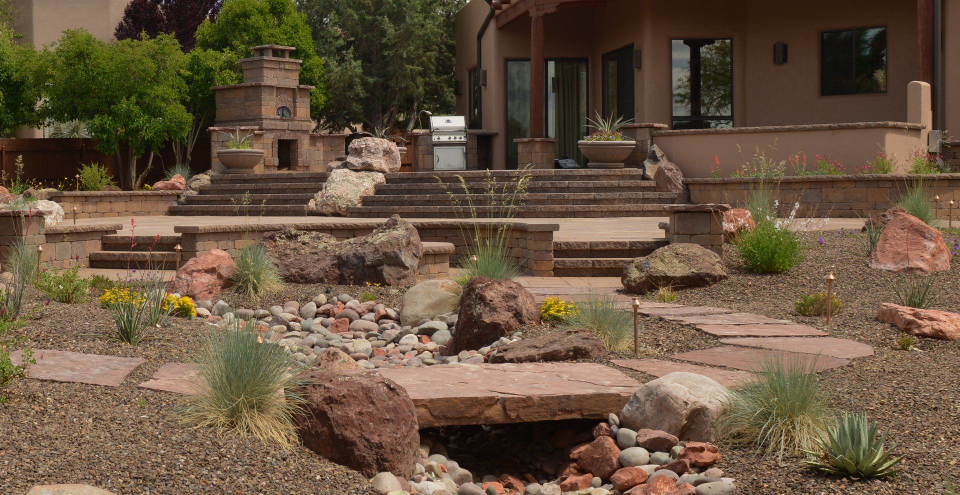 There is a fire pit in the middle of the patio under a blue umbrella.
