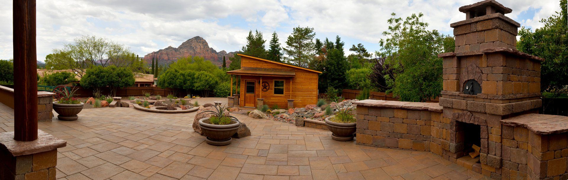 A patio with a fireplace and a house in the background.