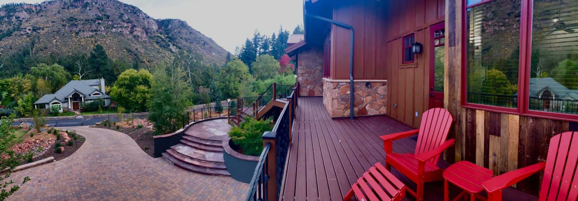 A balcony with red chairs and a mountain in the background.