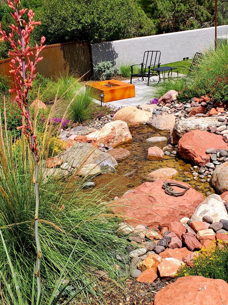 A stream running through a rocky garden with a bench in the background.