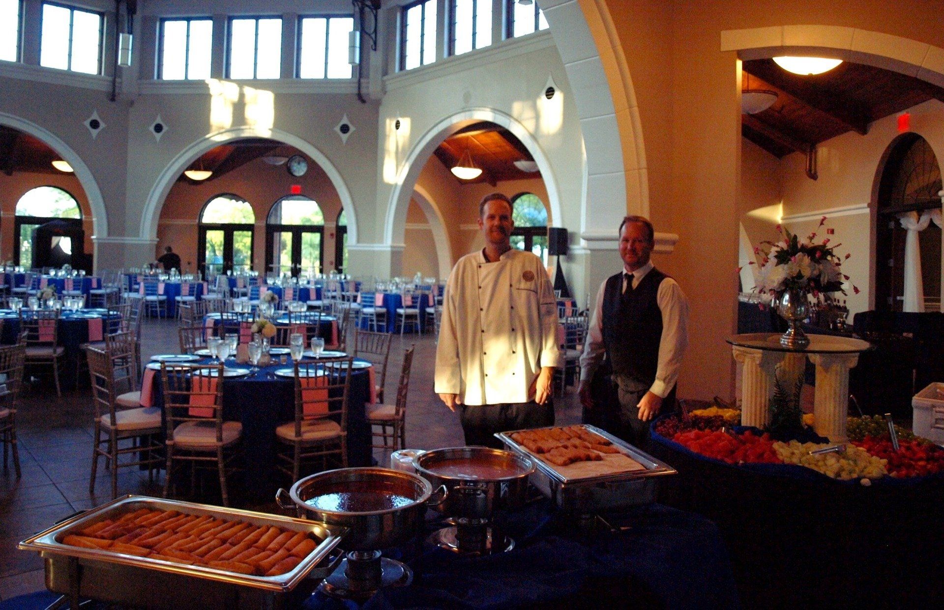 2 male caterers standing behind buffet table