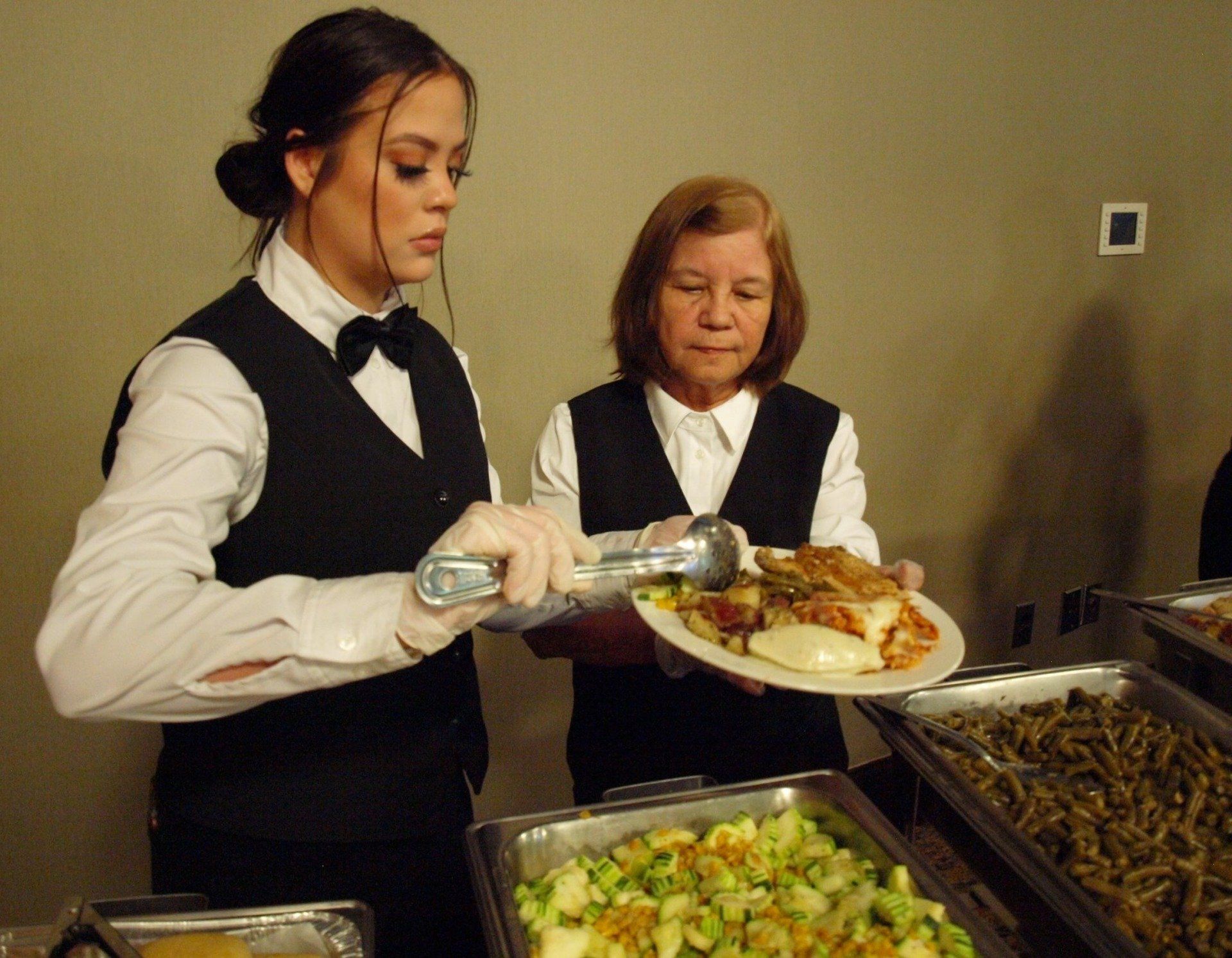 2 female caterers serving at a buffet table
