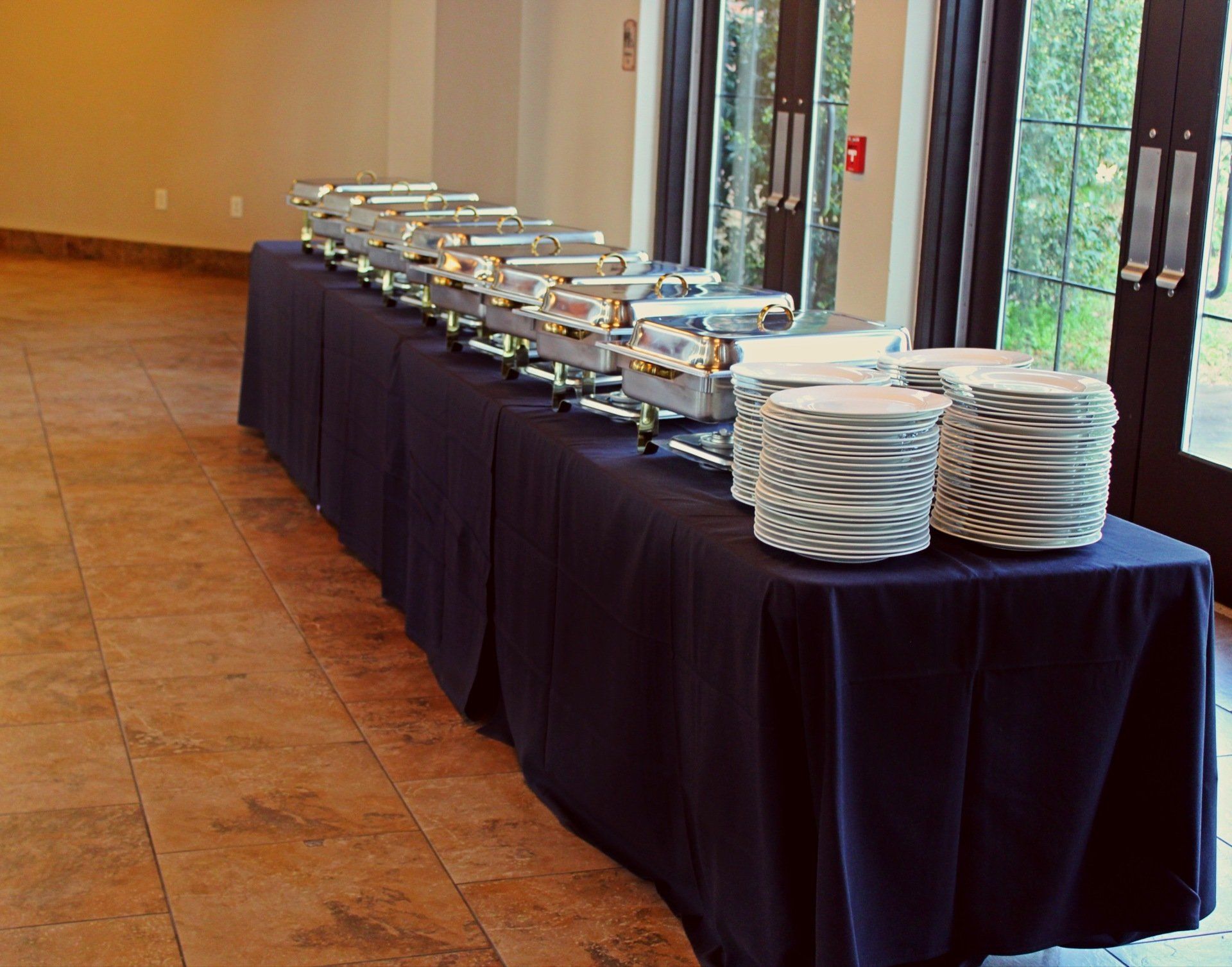 buffet table set with covered buffet pans and stacks of plates