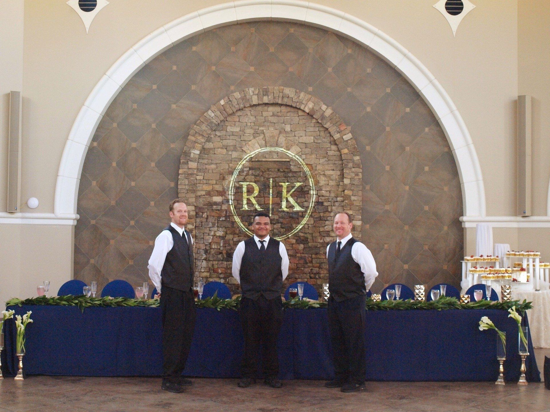 3 male caterers standing in front of wedding party table