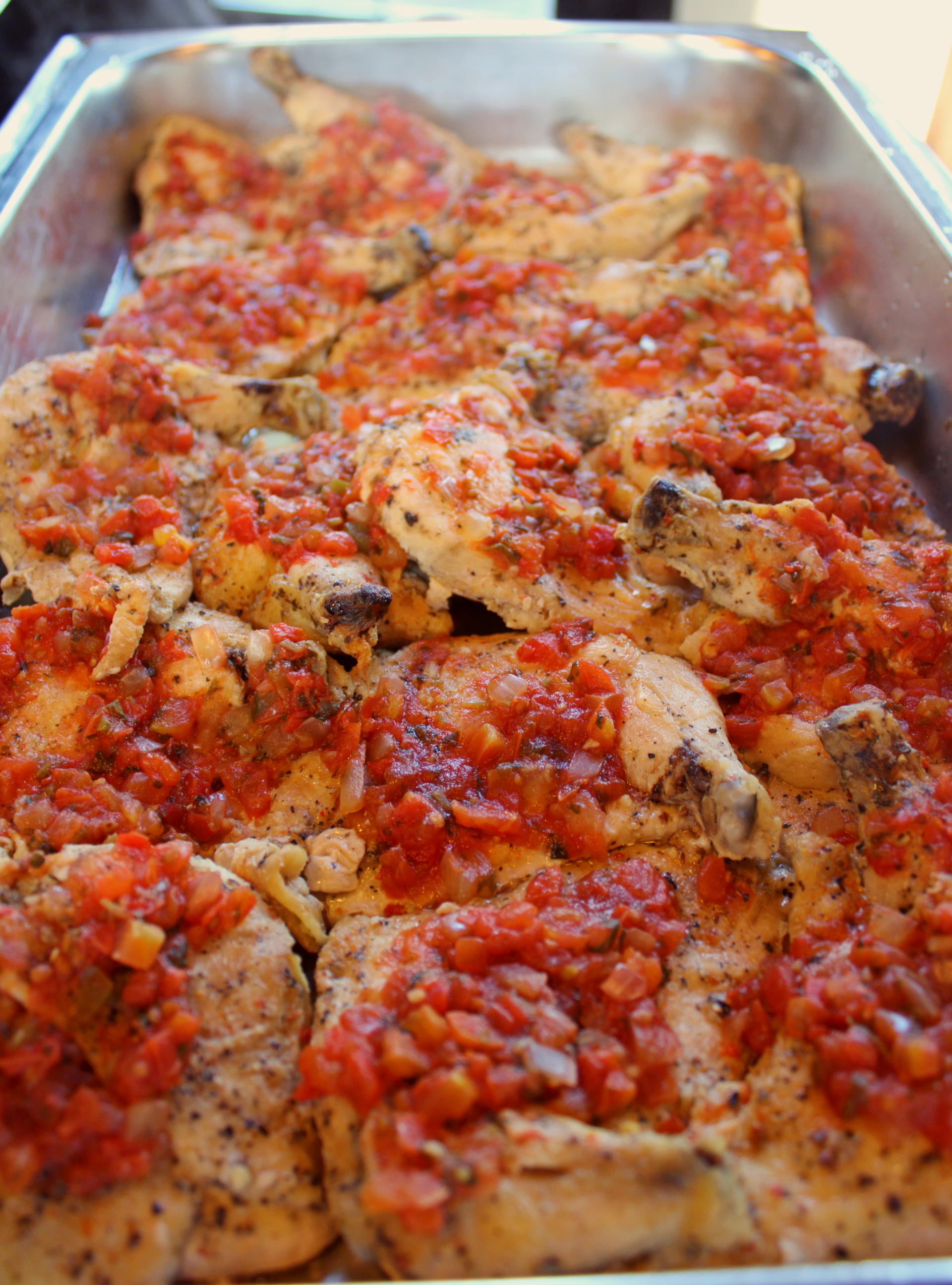 buffet pan filled with chicken topped with a red sauce