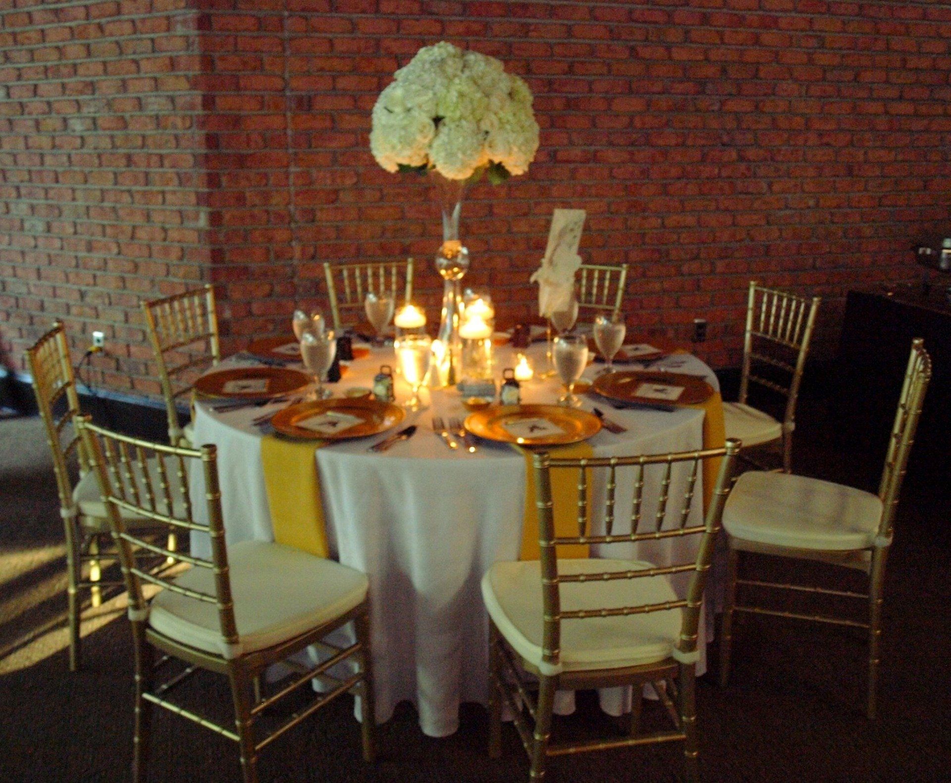 reund table set up with gold and white decor with tall floral centerpiece