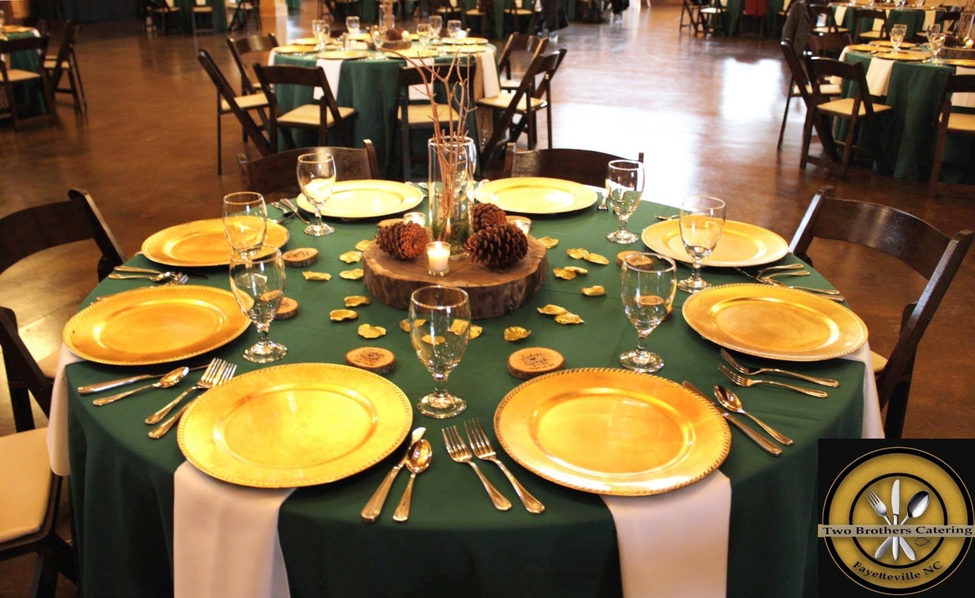 round table set with green and gold decor and rustic centerpiece