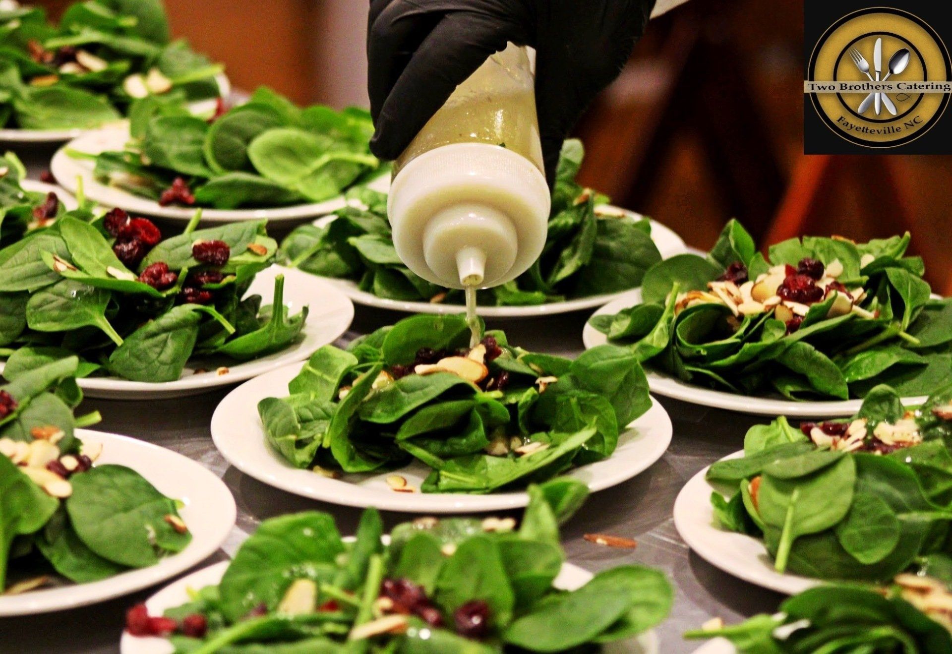 dressing being added to plated spinich salad