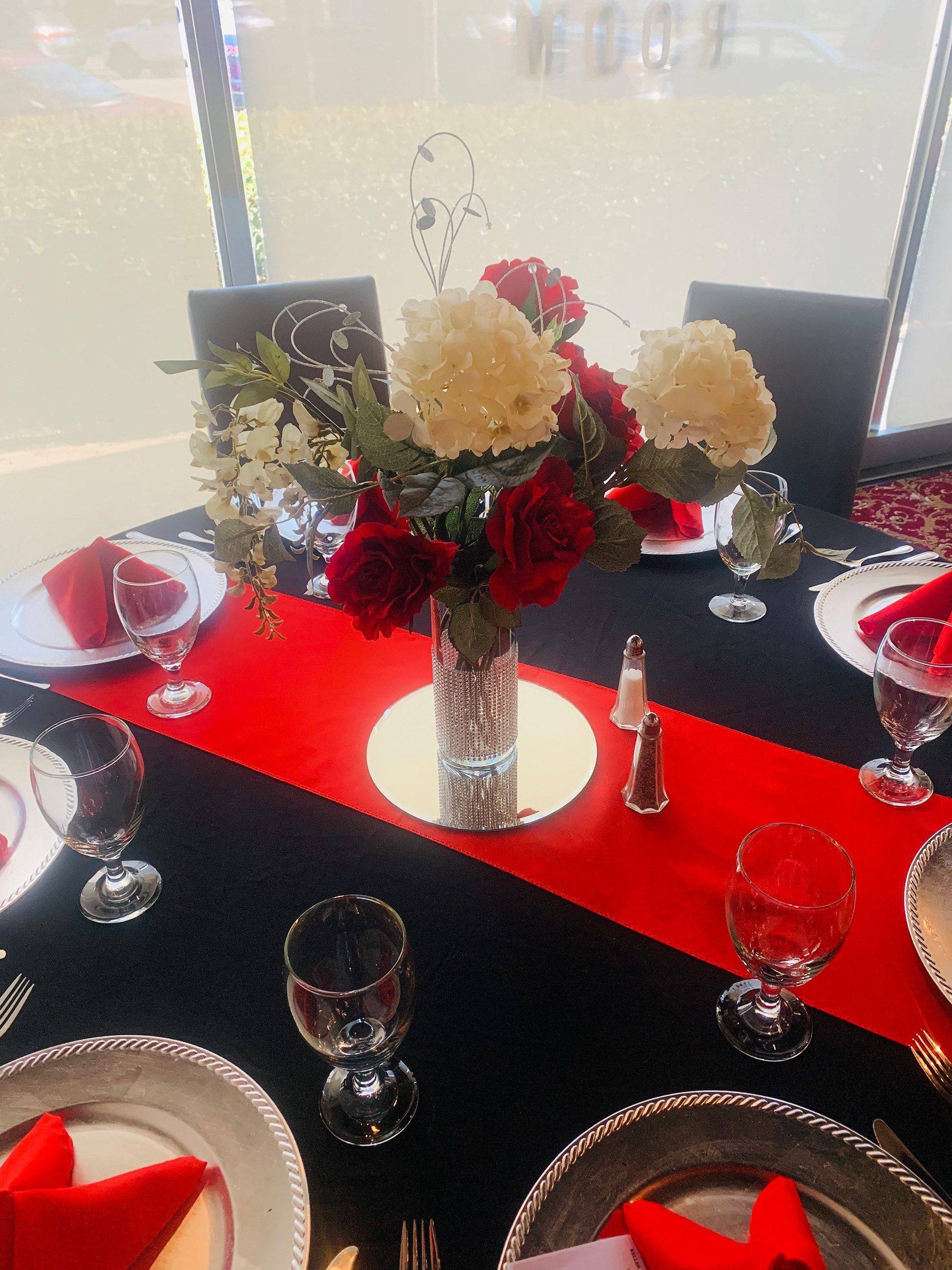 table setting with red and black decor and floral centerpiece