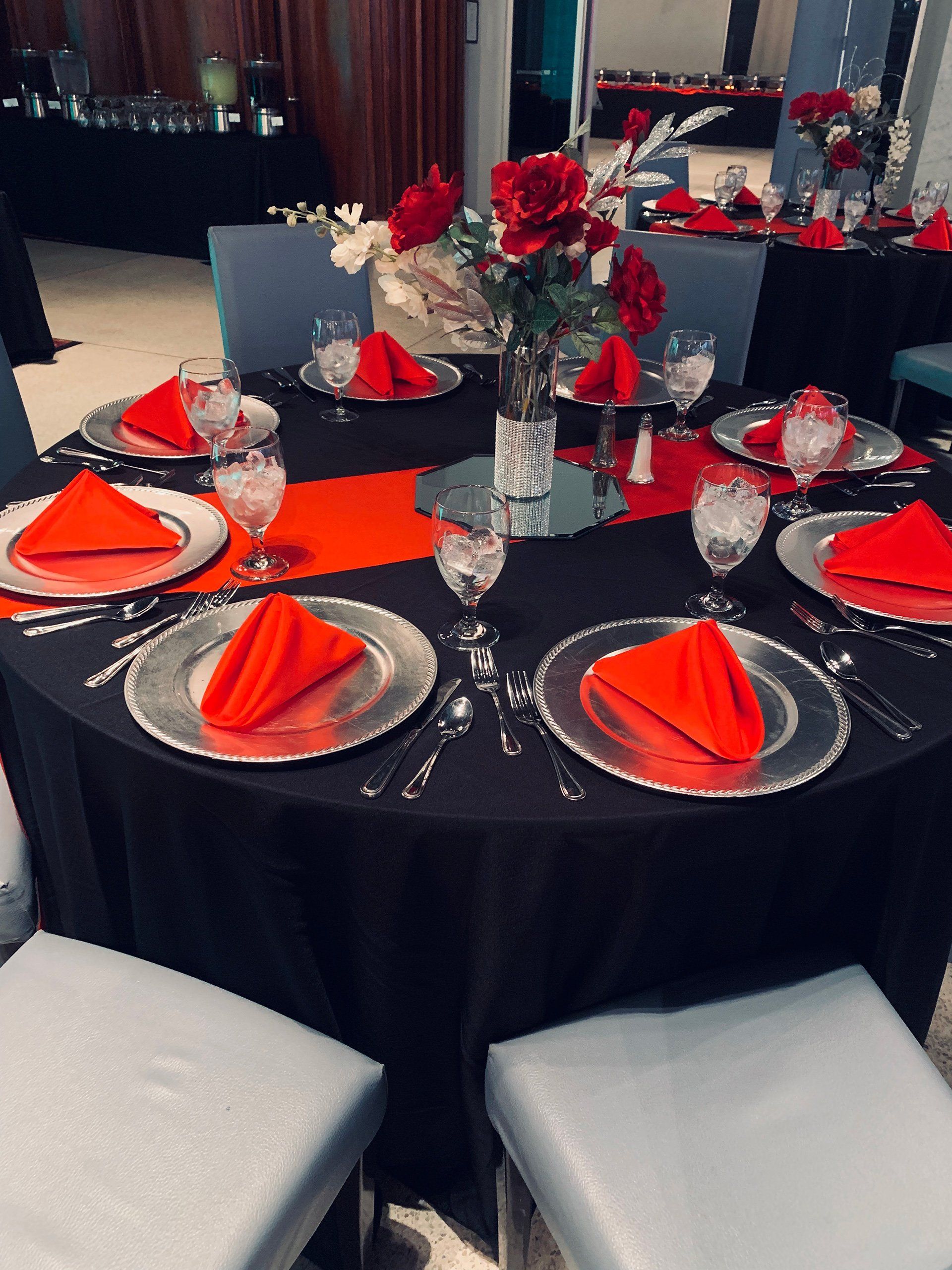 table setting with red and black decor with floral centerpiece