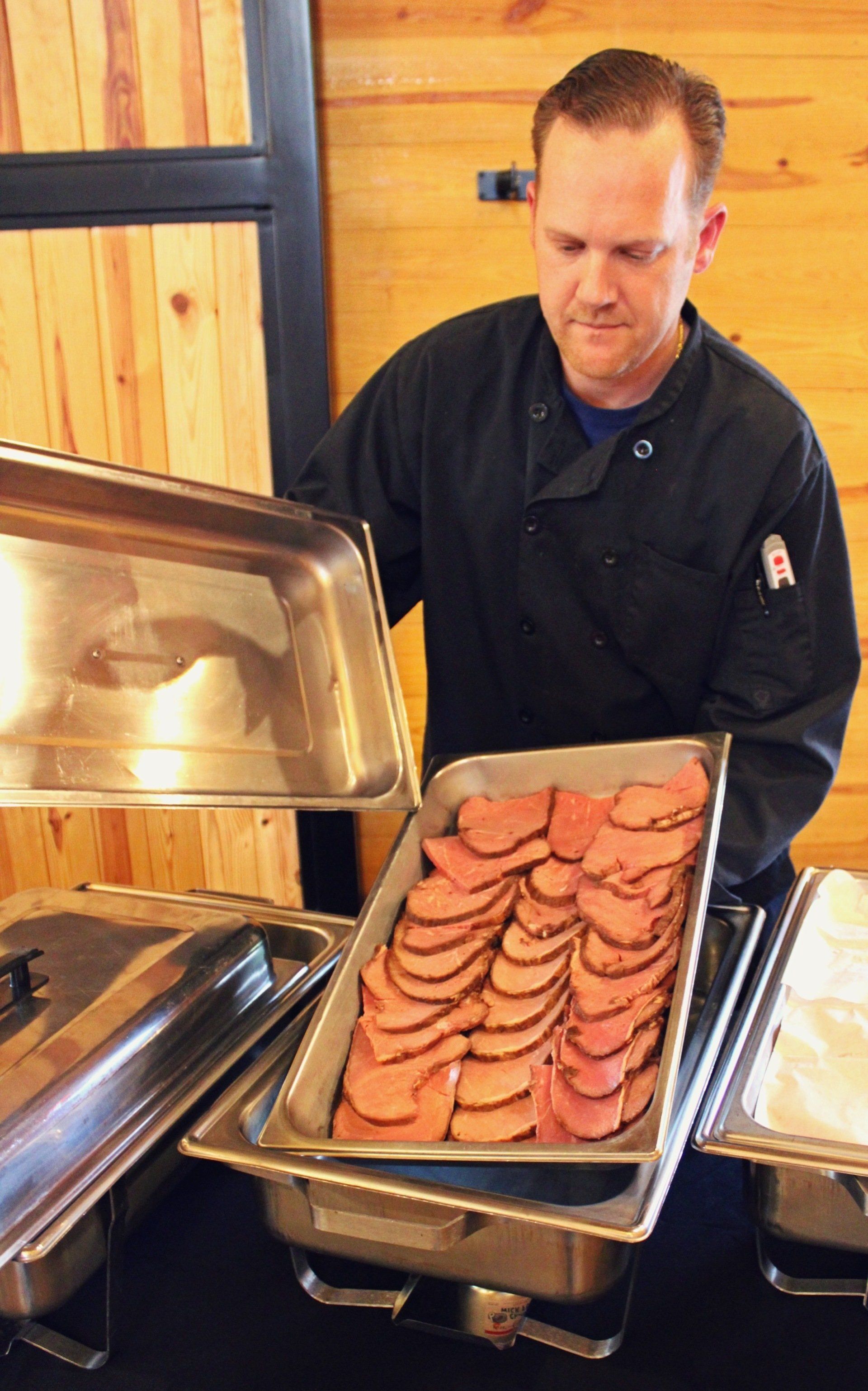 caterer putting out buffet pan of ham