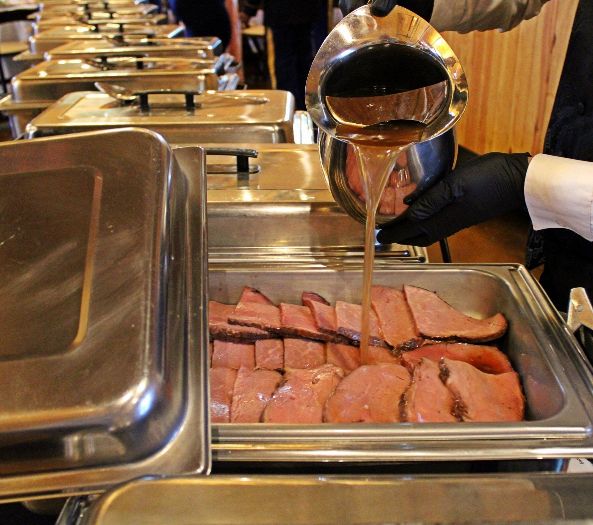 glaze being poured over a buffet pan of ham