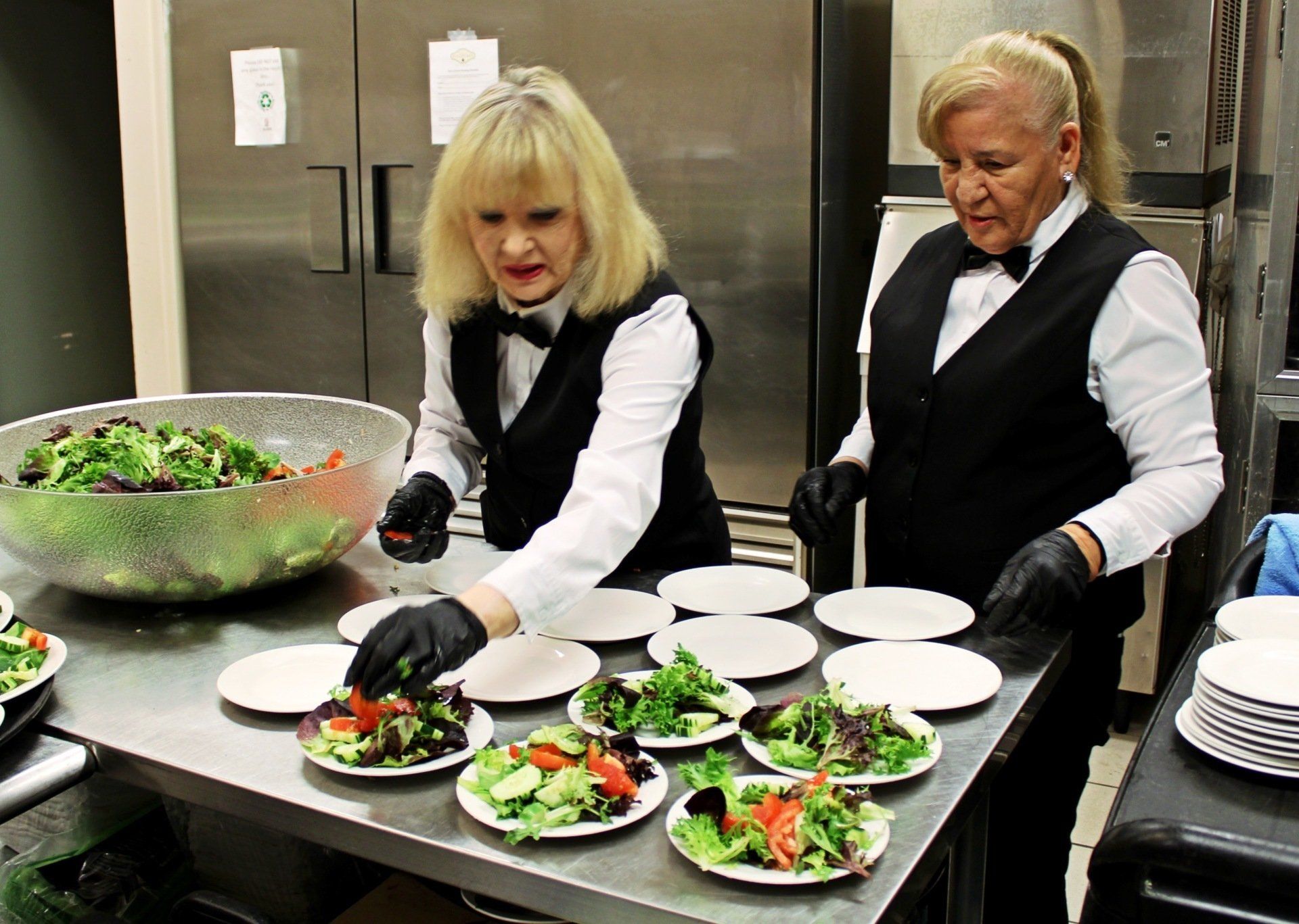 2 female caterers plating salad