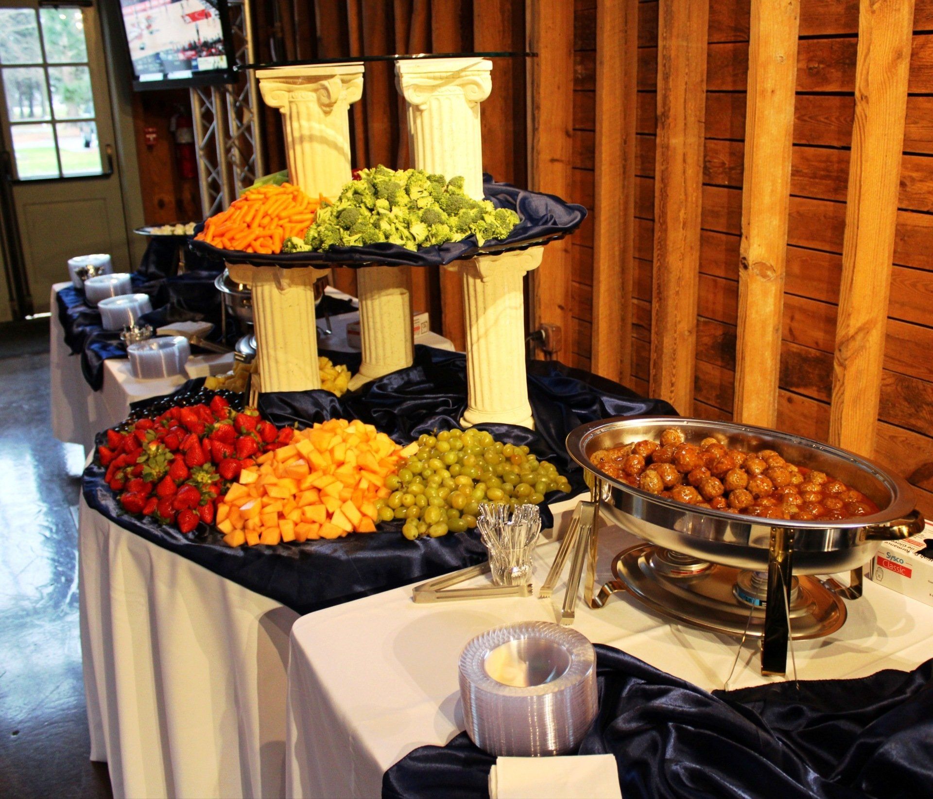 buffet table with 3 tiered fruit and vegetable display and a buffet pan of meatballs