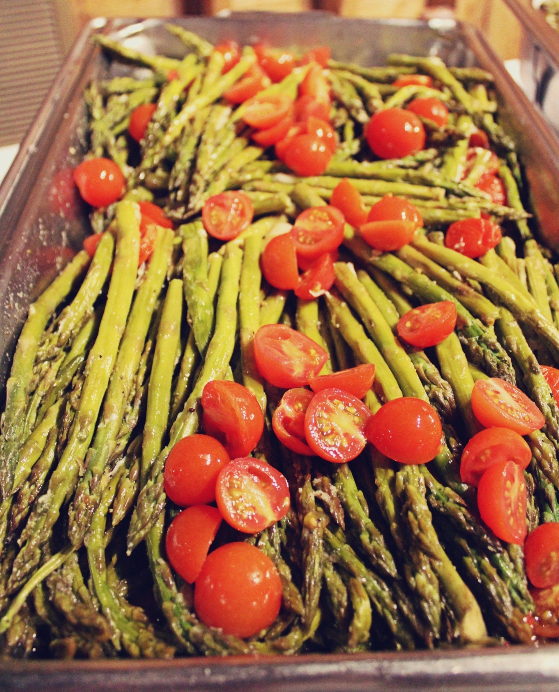 buffet pan filled with asparagus with cherry tomatoes on top