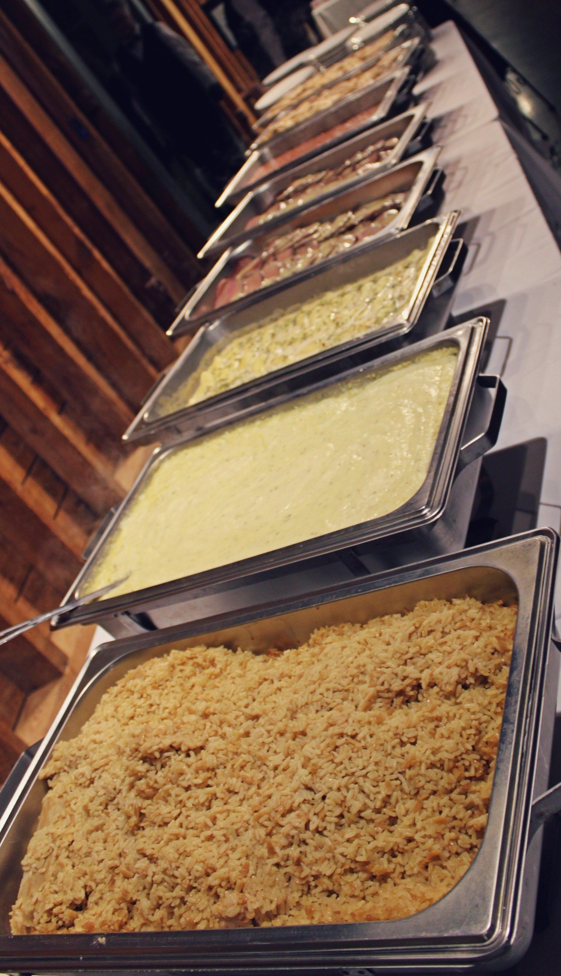 buffet pans filled with food lined up on buffet table