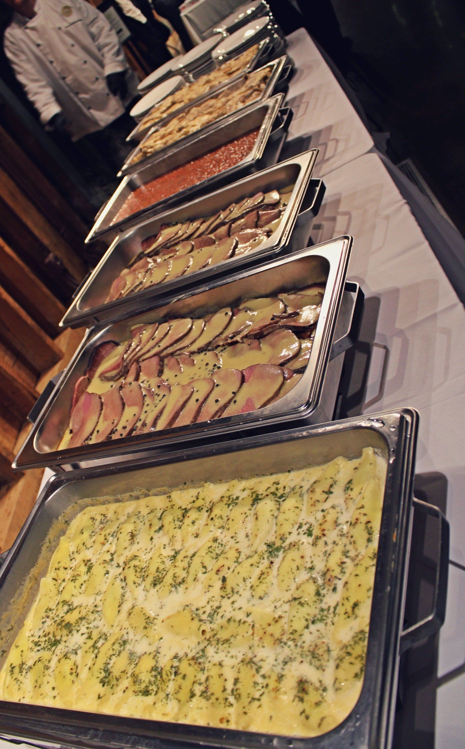 buffet pans filled with food lined up on buffet table