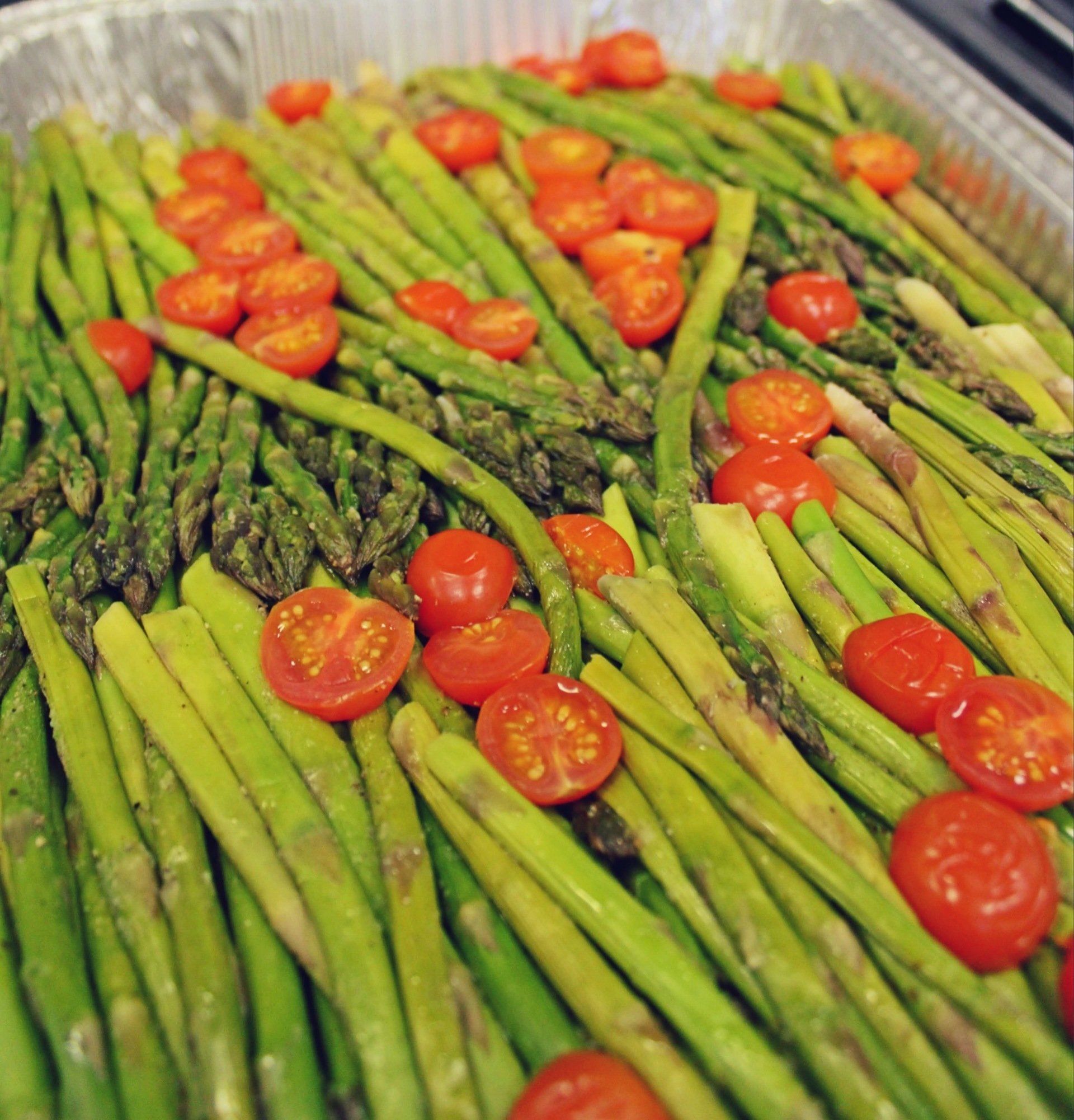 buffet tray filled with aspargus and topped with cherry tomatoes