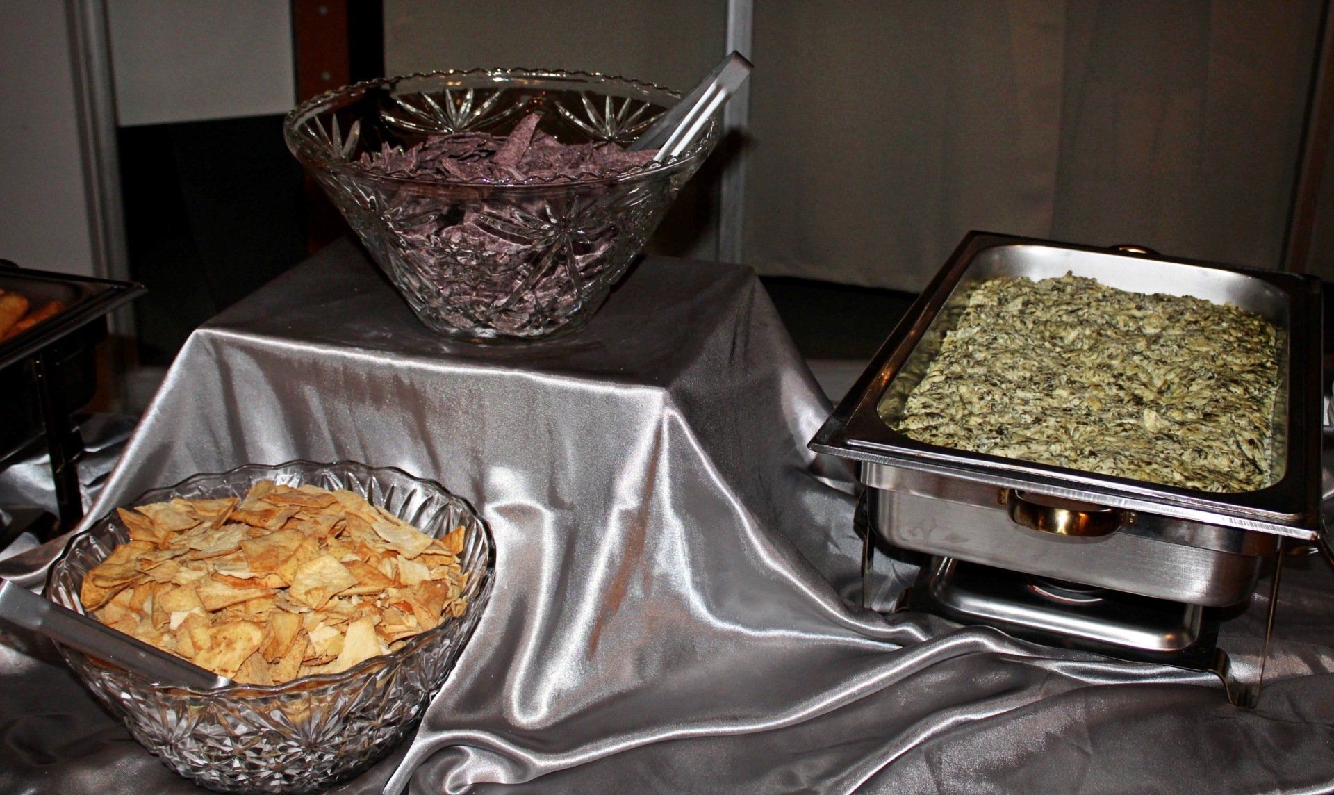 buffet pan filled with spinach and bowls of chips