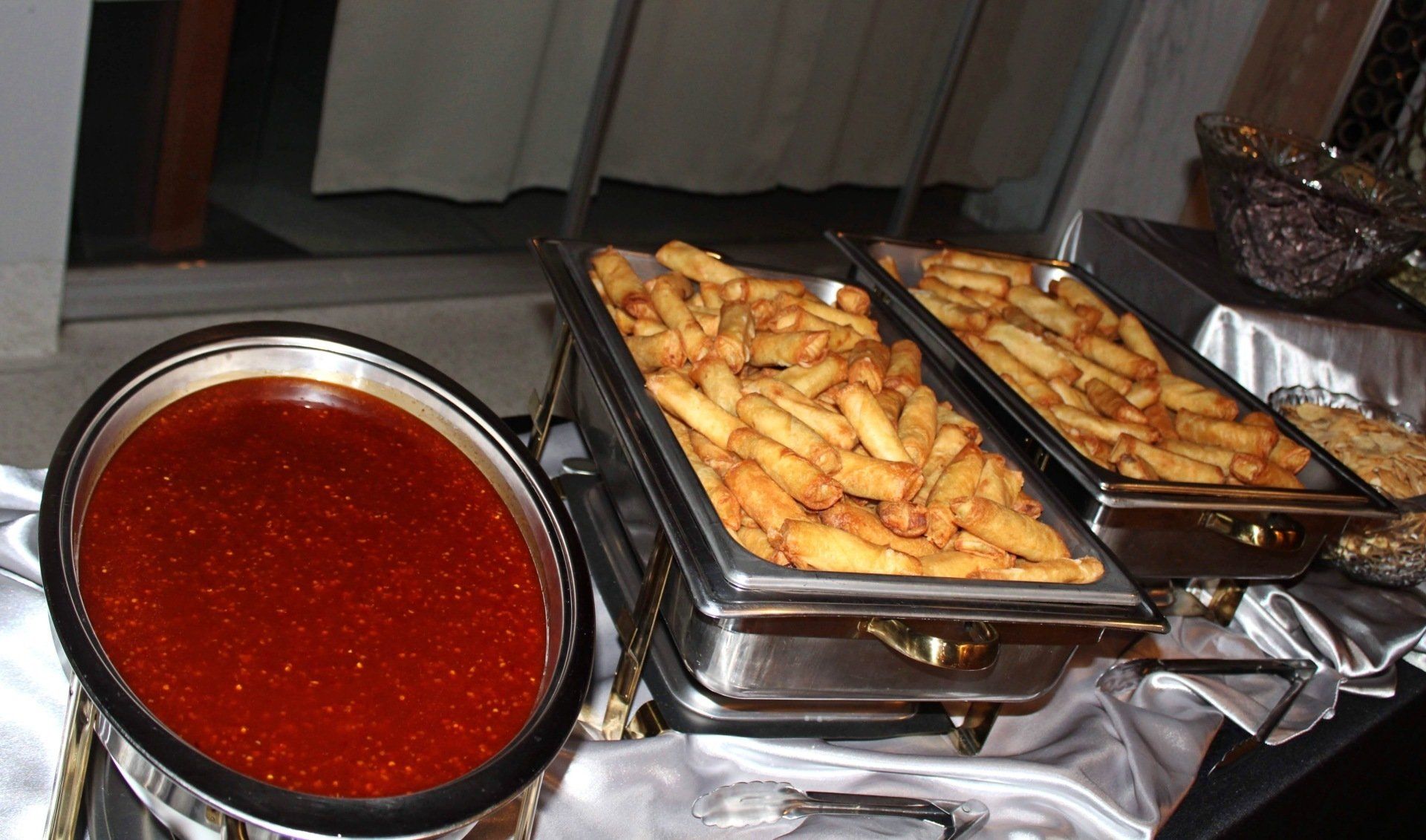 buffet pans filled with egg rolls and dipping sauce