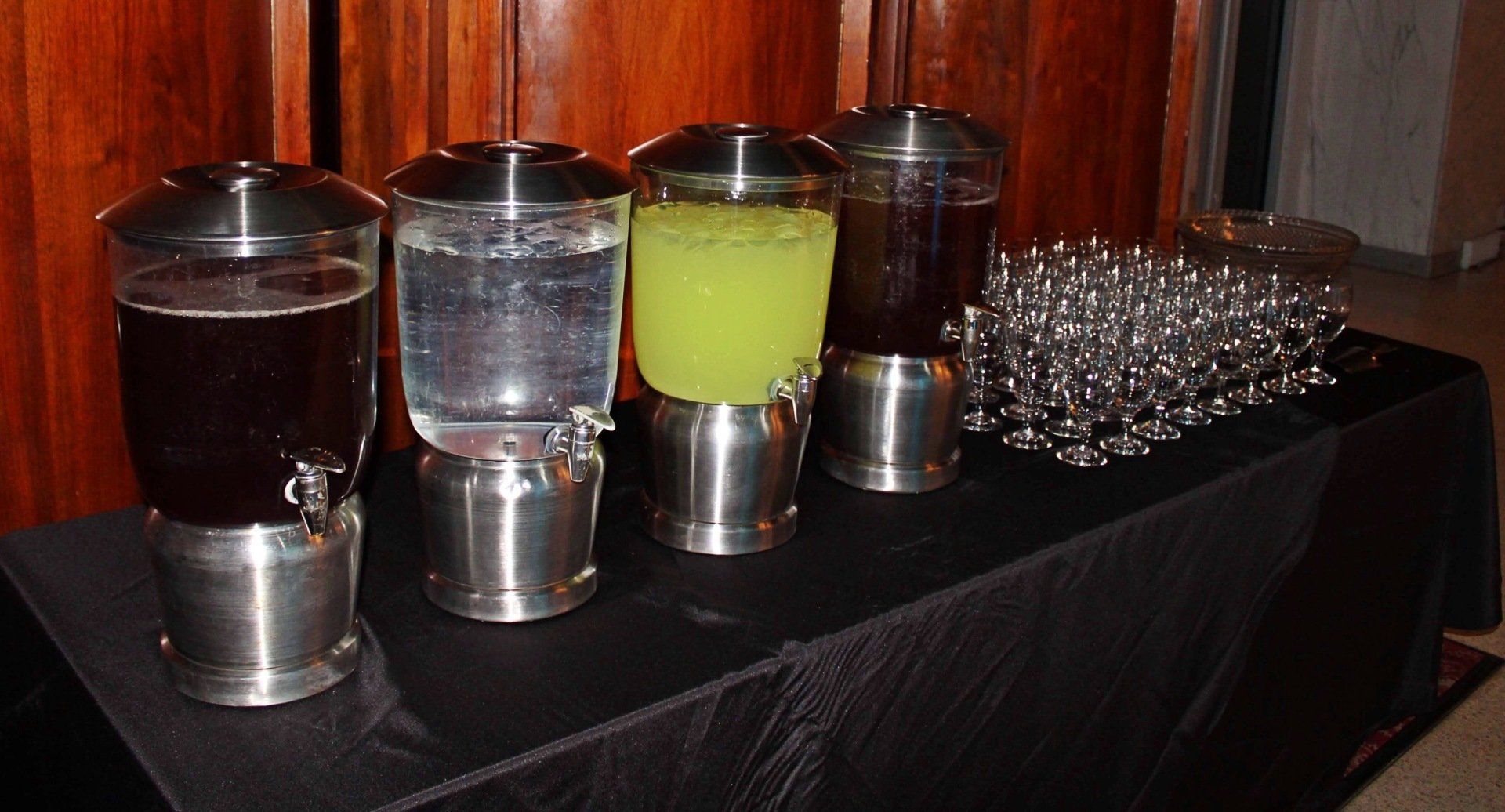 4 beverage jars and glasses on a beverage table