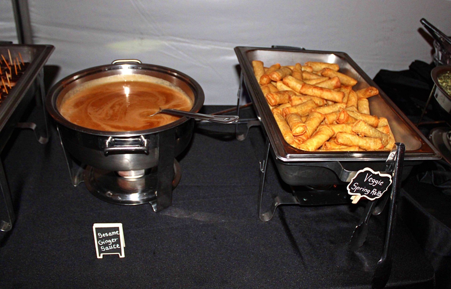 buffet pan filled with spring rolls and dipping sauce