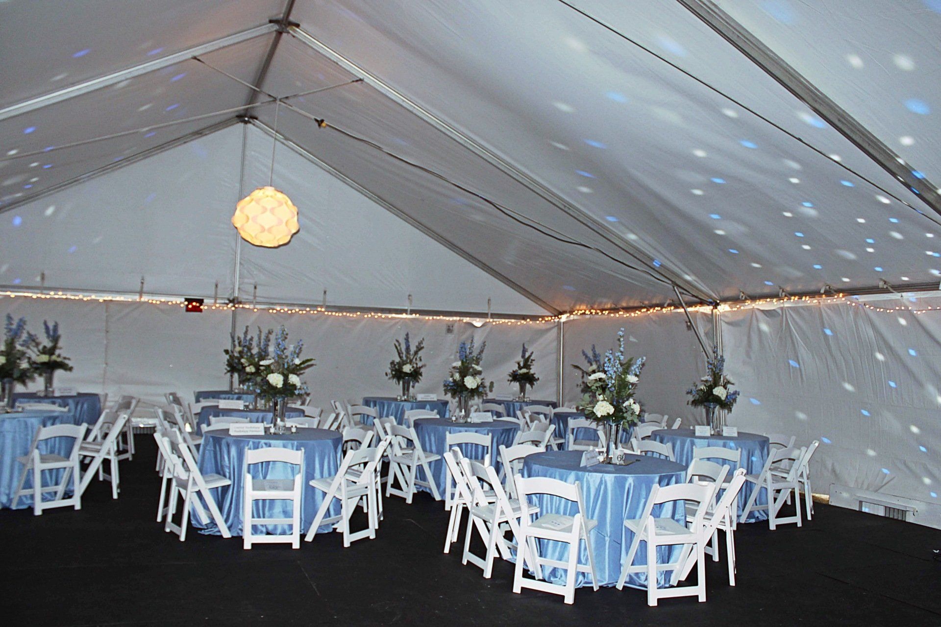 teneted room set up with blue and white decor and floral centerpieces