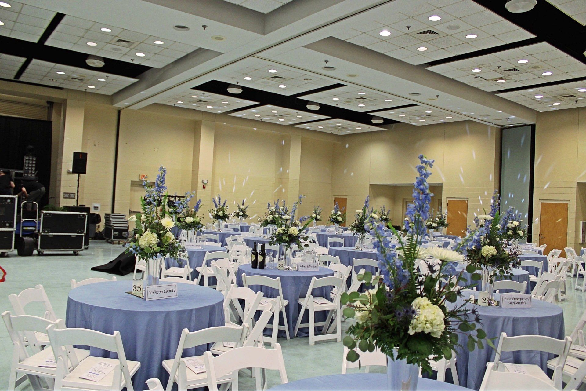 room set up with round tables in blue and white decor and floral centerpieces