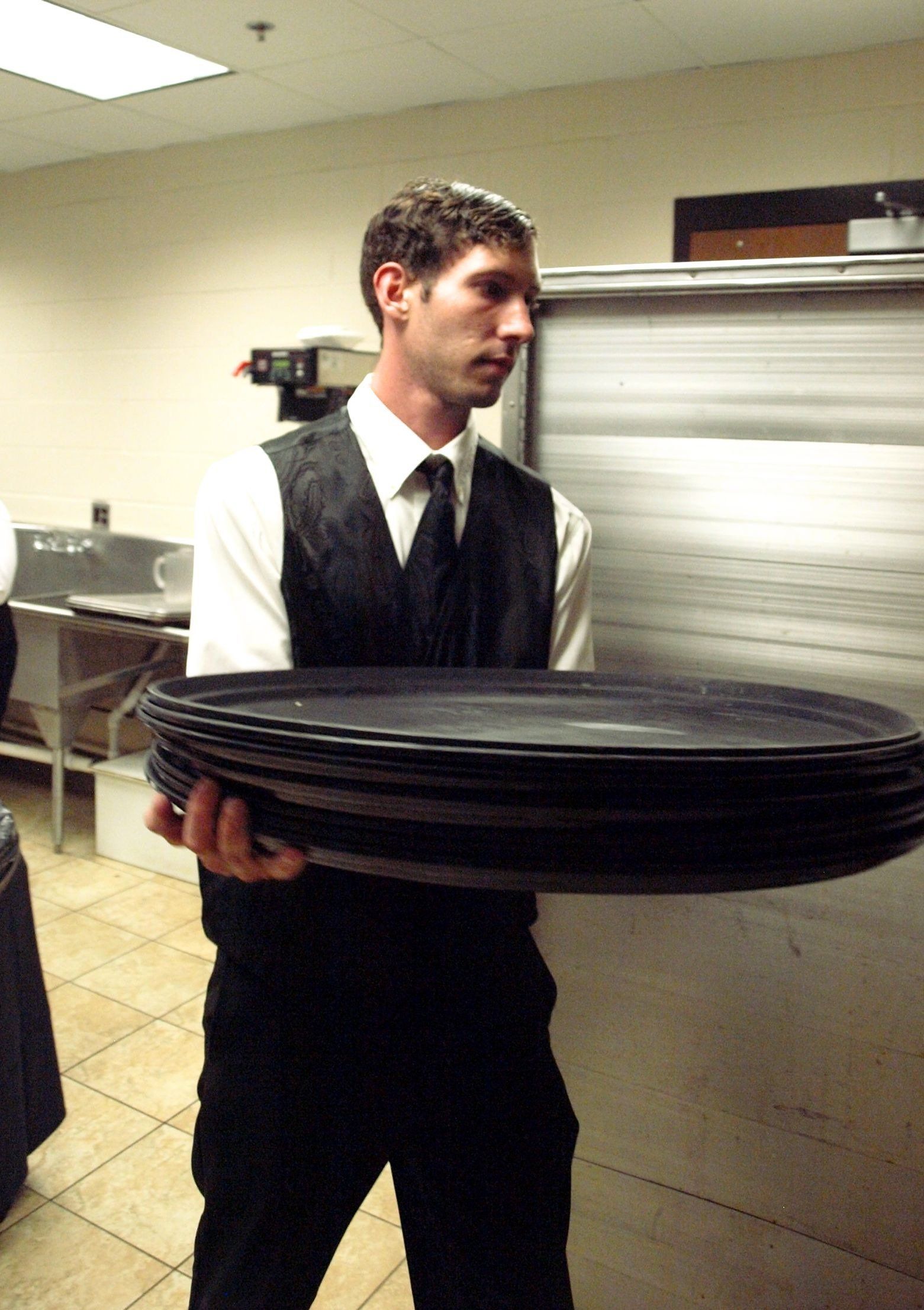 male caterer carrying a stack of trays