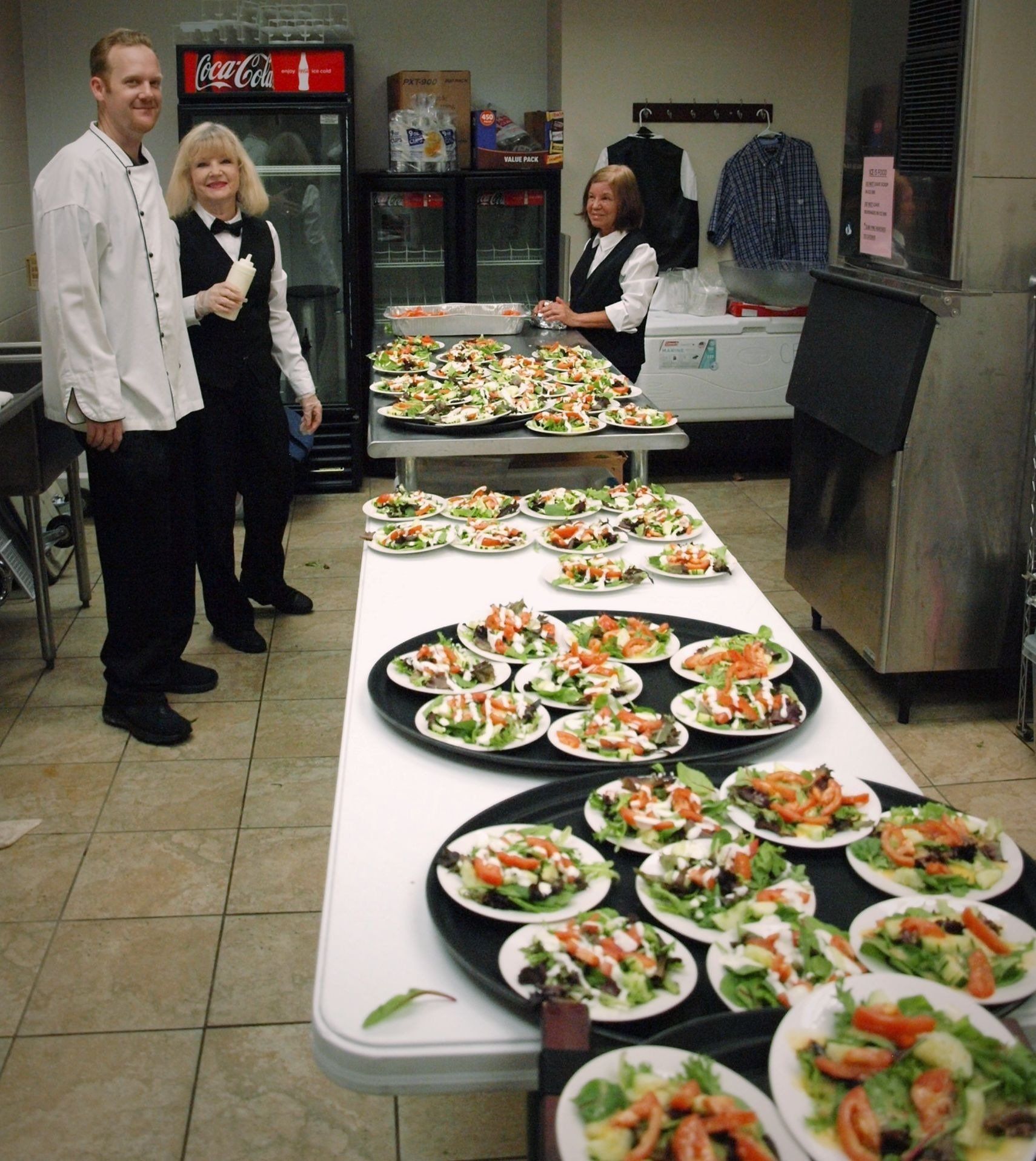 caterers standing in front of table of plated salads