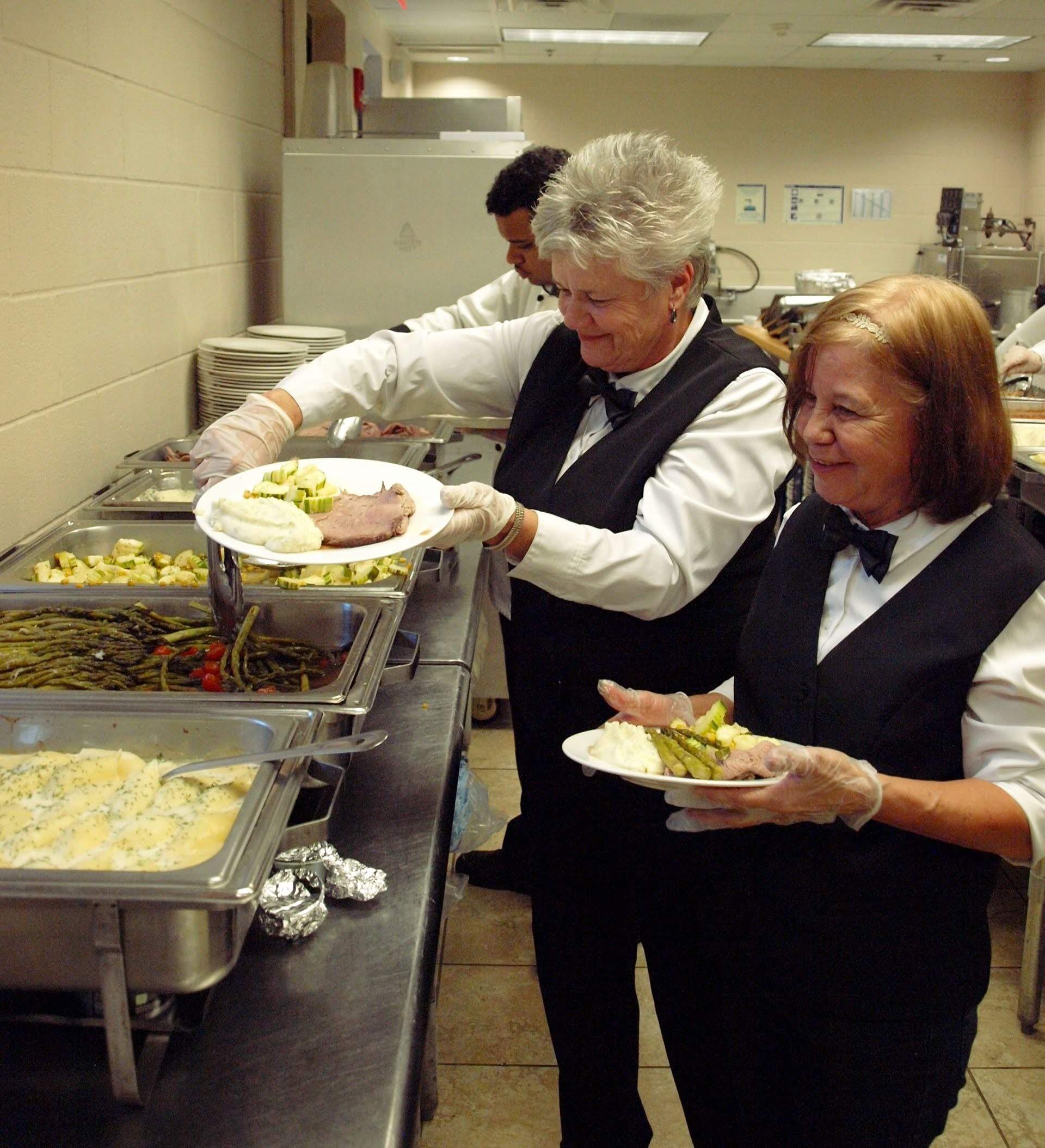female caterers plating food in a buffet line