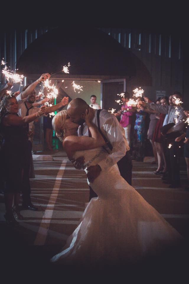 wedding couple kissing while guests celebrate with sparklers