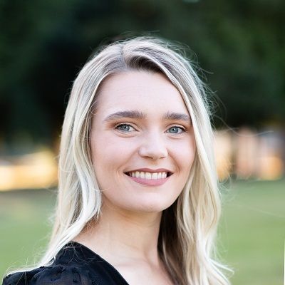 A woman with blonde hair and blue eyes is smiling for the camera.