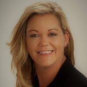 A woman with long blonde hair is smiling and wearing a black shirt.