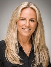 A woman with long blonde hair is smiling and wearing a black shirt.