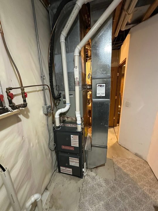 A vertical high-efficiency gas furnace and metallic ductwork in a residential basement.