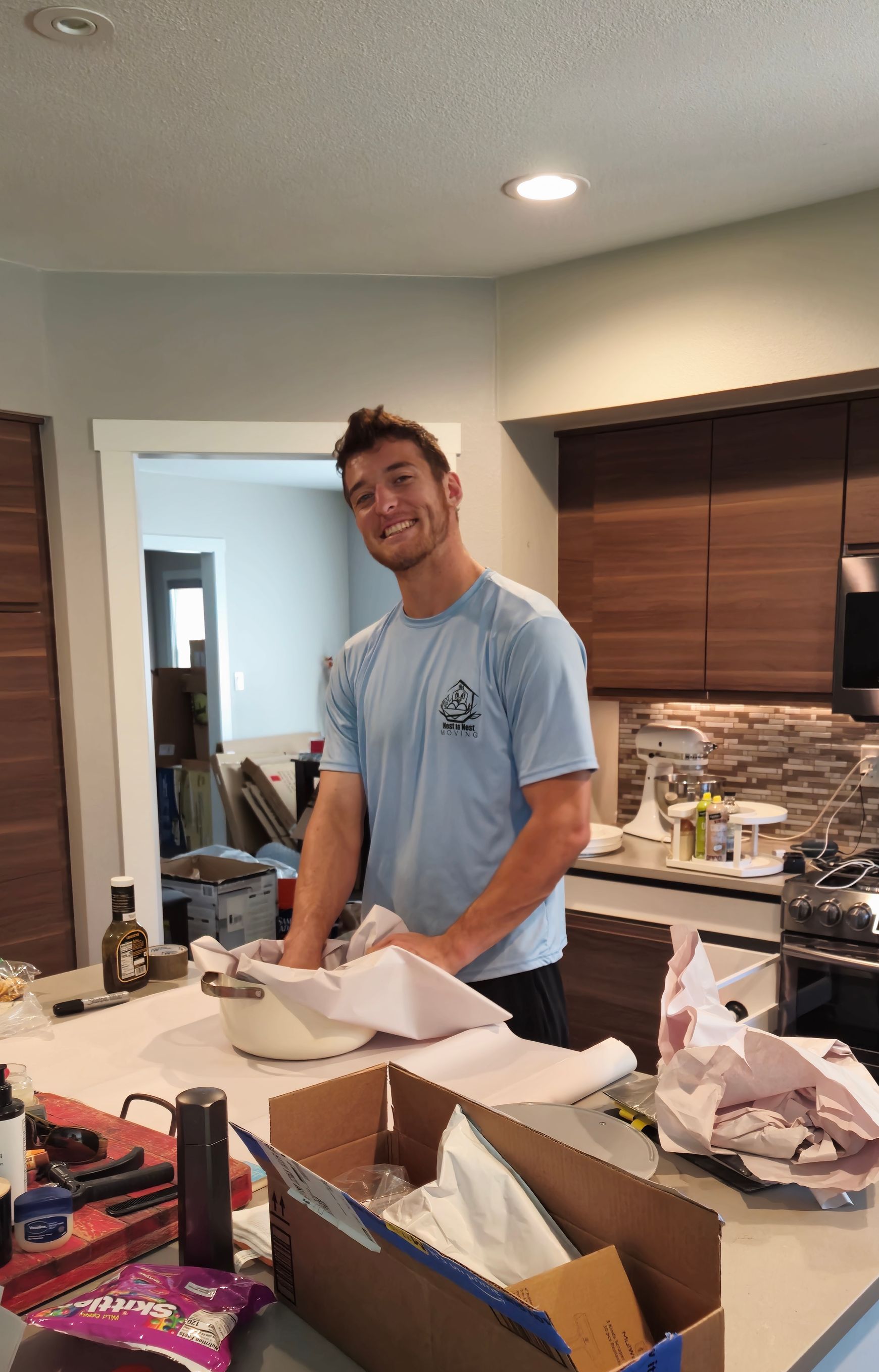 A man in a blue shirt is standing in a kitchen.