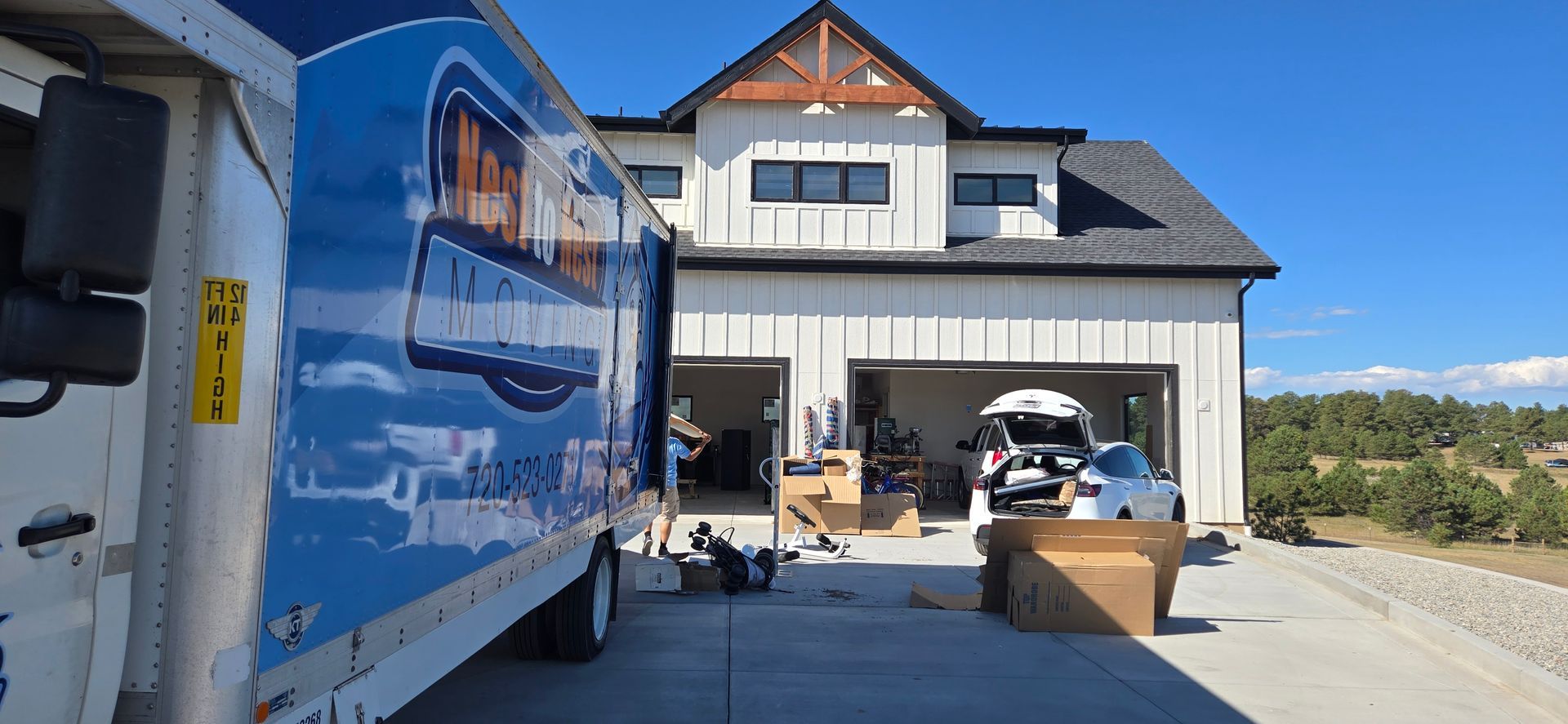 A moving truck is parked in front of a large house.